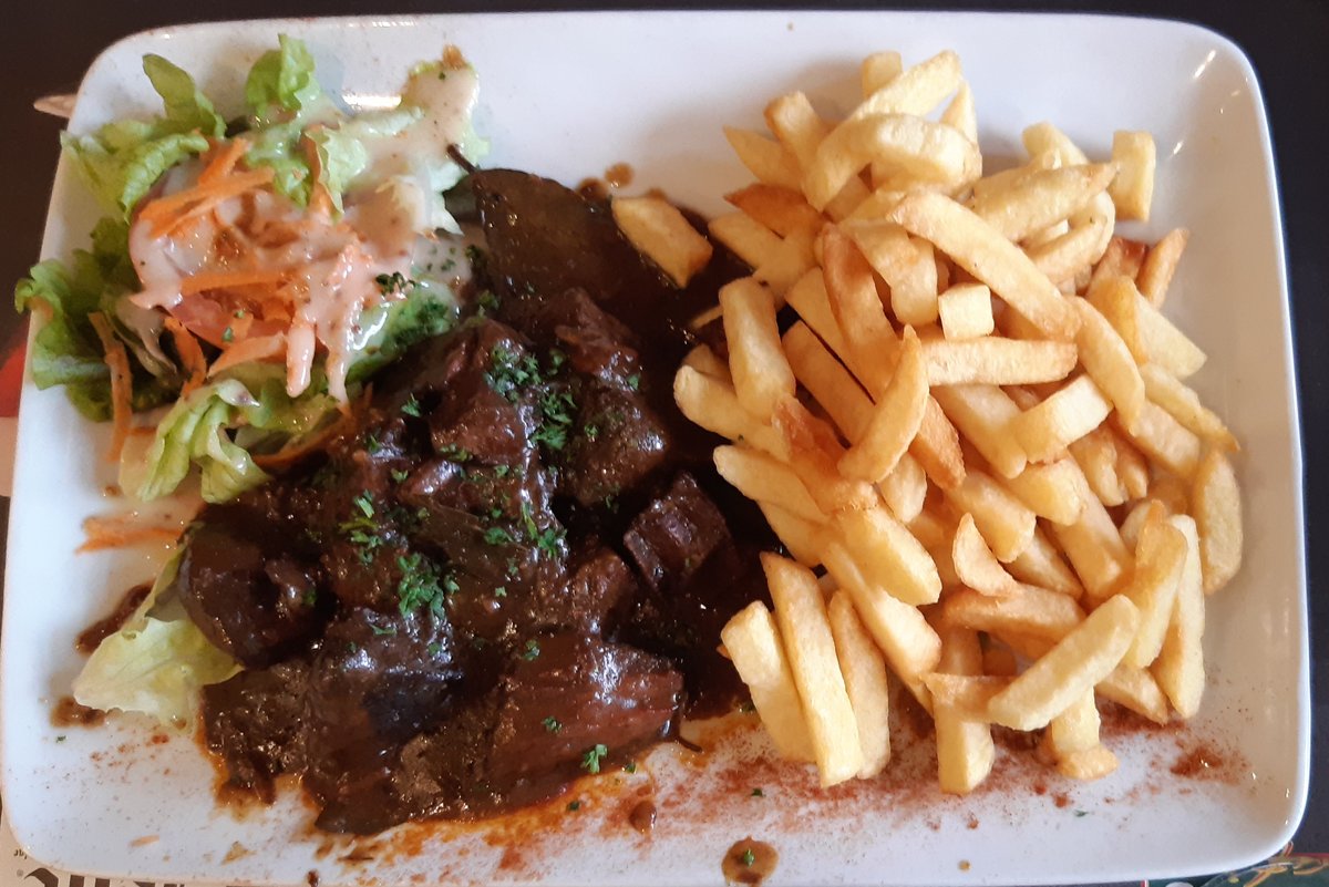 Assiette de carbonnade flamande servie avec des frites et une petite salade