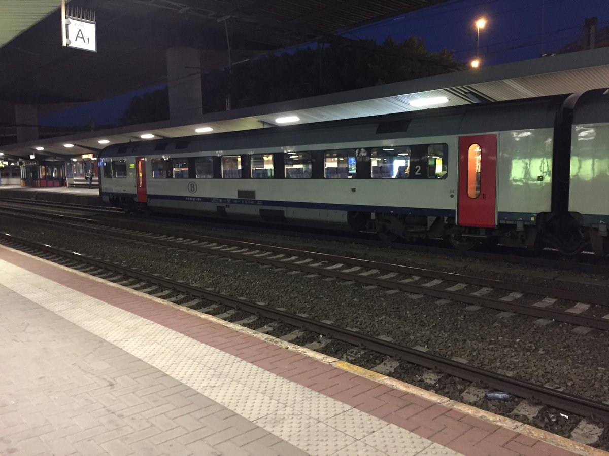 Train de voyageurs à quai, le soir, dans une gare belge